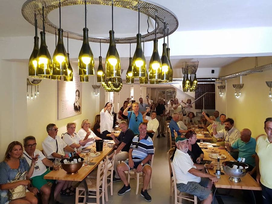 tourists smiling happily at the camera and tasting wine at 'Zoinos Winery'